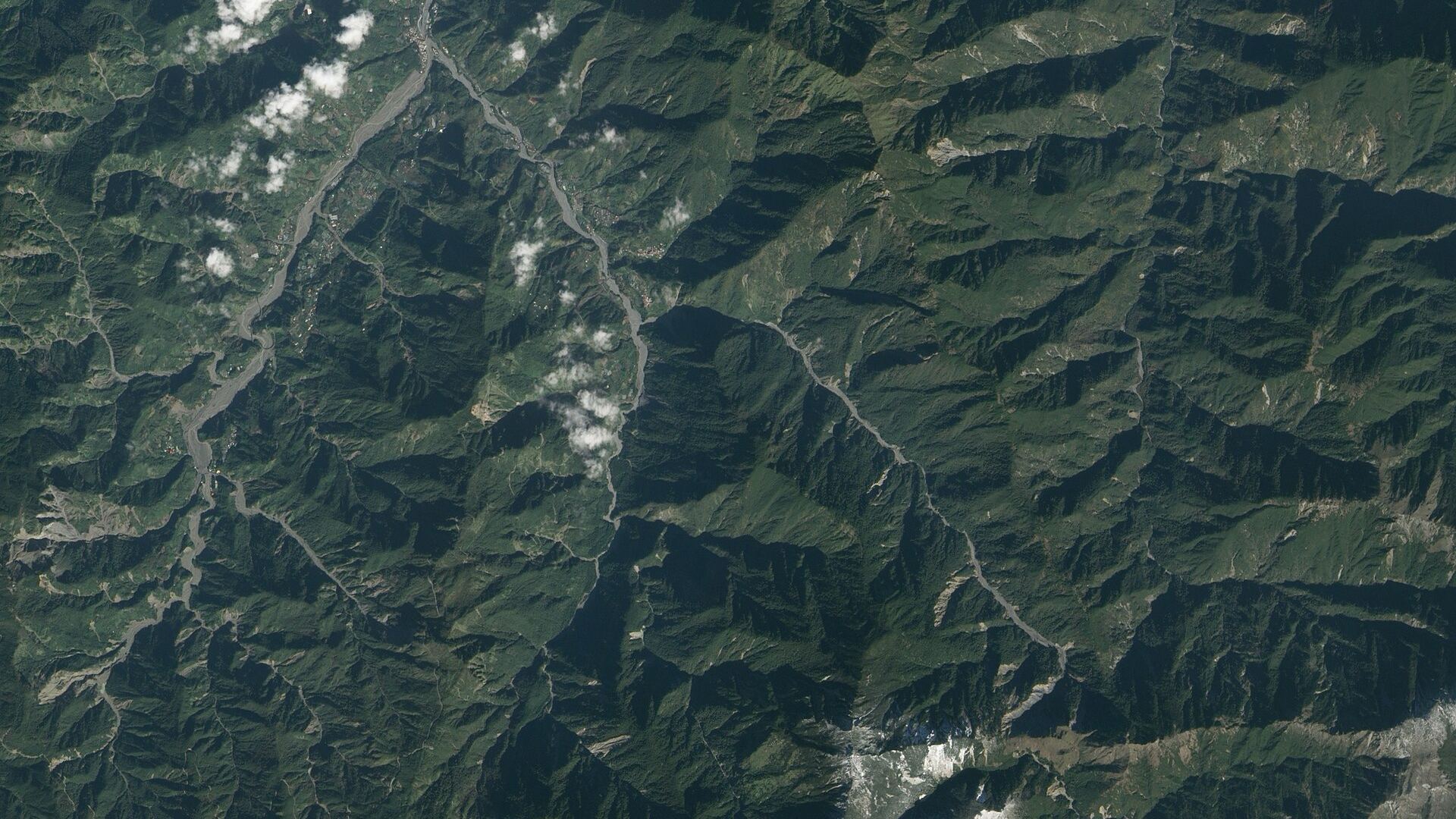 從衛星往下看的臺灣中部山區：綠色山脊之間有河谷，坡面上散布淺色的崩塌痕跡