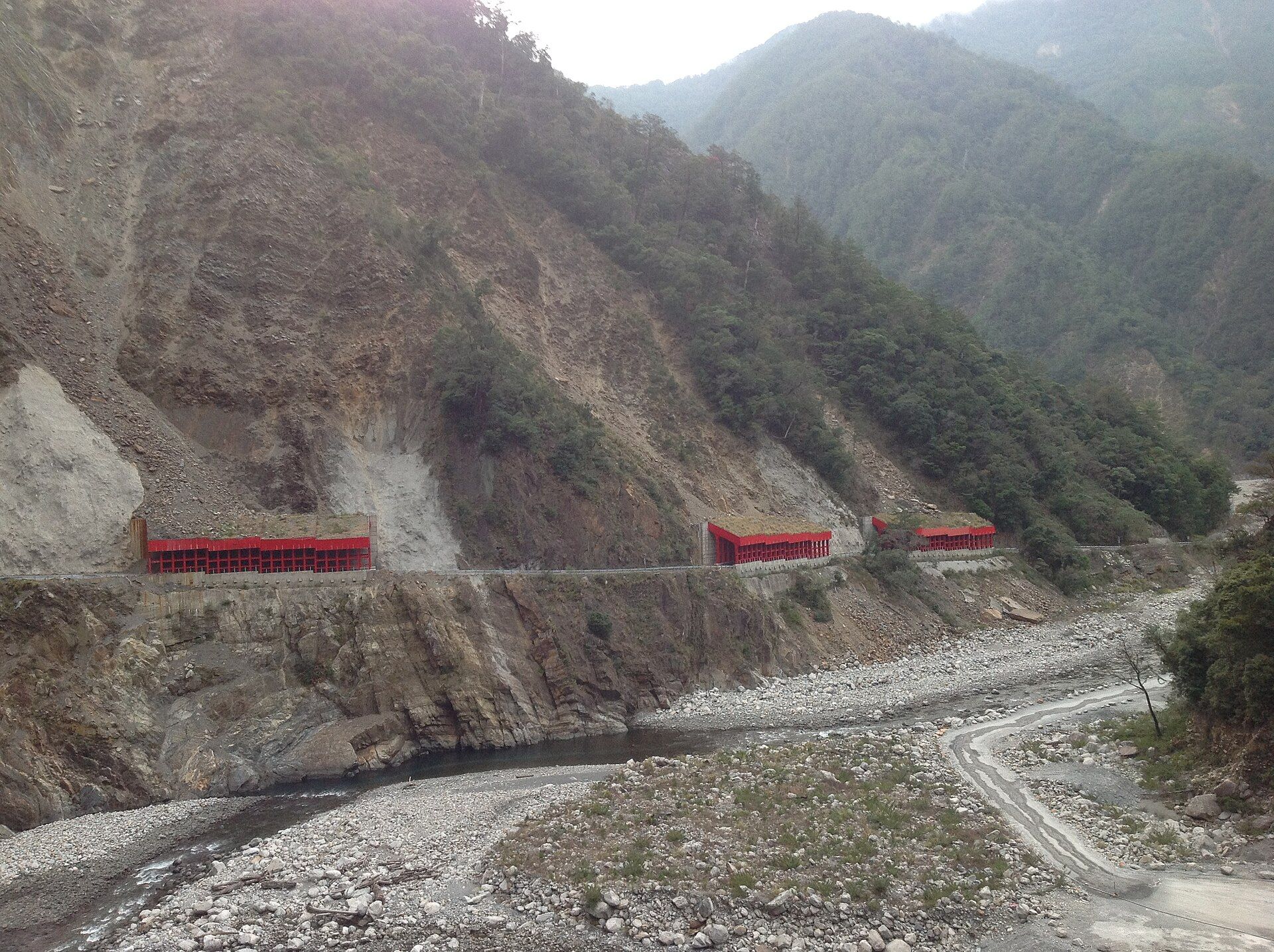 台 8 線臨 37 線便道旁的大片崩塌坡面，紅色明隧道沿河谷貼著山壁